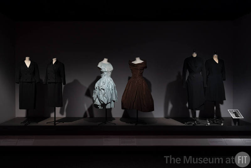 Dior + Balenciaga, Left to right PL74.1.30 (suit), 77.116.5 (suit), 70.57.54 (blue cocktail dress), 69.153.3 (brown cocktail dress), PL74.1.2 (black wool ensemble), P91.78.2 (black coat dress)