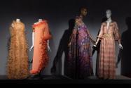 Dior + Balenciaga, Left to right 87.19.1 (ostrich feather dress), 89.160.2 (orange evening gown), 73.73.1 (multicolor evening dress and scarf), 80.58.5 (printed pink and gold metallic evening dress)