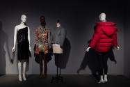 Dior + Balenciaga, Left to right: 2008.60.1 (black one shoulder dress), 2005.23.1 (graffiti knit dress), 2019.21.1 (jacket), 2016.113.1 (red puffer coat)