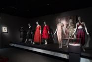 Trendology_28 Left to right 93.51.1 (ensemble), 68.136.3 (dress), 77.115.5 (lace dress), 76.29.39 (red dress),  97.24.12 (textile wall), 77.186.40 (jumpsuit), P84.32.1 (swimsuit), 72.61.56 (top and pants), 2011.43.2 (gloves case) 