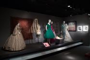 RetroSpective_32 Left to right P88.14.5 (dress), 86.157.9 (shawl wall), 84.26.2 (hoop hanging), 2001.73.1 (crinoline), 92.59.1 (green dress), 2001.73.1B (hoop package),  P91.38.4 (hoops case), 2007.33.2 (purple and white dress), 2013.20.1 (ensemble), 91.187.21 (textile wall), 2007.53.1 (wedding gown), 94.5.1 (scarf side wall)