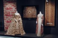 Exoticism_10 Left to right 2005.64.4 (textile wall),  P82.27.1 (dress), 82.142.6 (textile wall), P89.40.6 and P86.71.1 (white dress and shawl), X321.29A (textile wall)