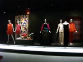 Rainbow_67 Left to right  82.3.2 (orange dress), 70.62.1 (pink dress), 2003.89.1 (textile wall), U.368 (shoes case), 2004.50.2 (earrings case), 2005.77.3 (hat case), 91.14.5 (bag case), 83.164.2 (shoes case), 84.145.1 (evening gown), 93.129.3 (satin pantsuit), 83.13.6 (black dress), 96.119.11 (red ensemble), 94.85.12 (textile wall)