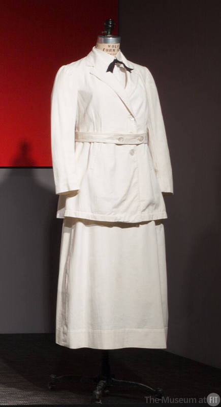 White suit with below hip length button front jacket, matching belt and ankle length A-line ski…