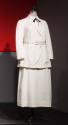 White suit with below hip length button front jacket, matching belt and ankle length A-line ski…