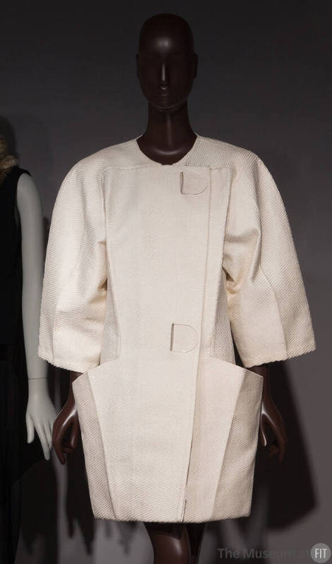 White textured oversize collarless short coat with two large clear hook closures, seam pockets