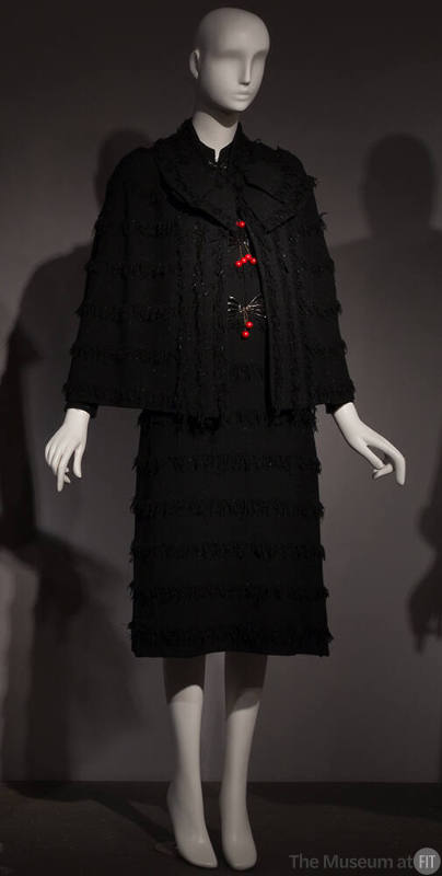Black long sleeve cape and knee length sheath dress set with horizontal stripes of fringe, larg…
