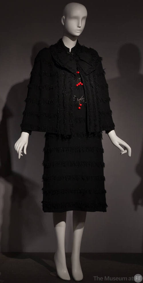 Black long sleeve cape and knee length sheath dress set with horizontal stripes of fringe, larg…