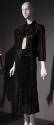 Black suit with fitted, tie collar jacket, calf length A-line skirt and white button front shir…