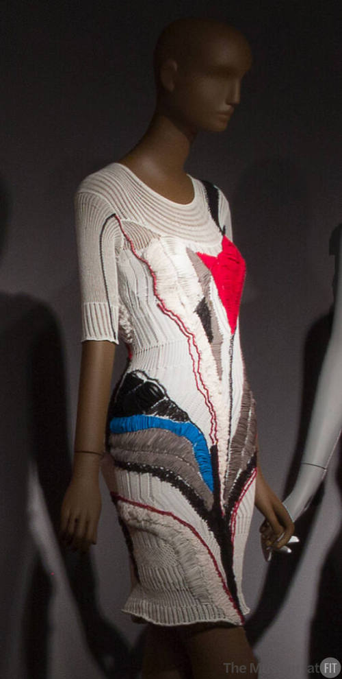 White knit above-the-knee dress with red, blue black and grey abstract stitching, 3/4 sleeves a…