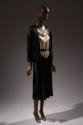 Black jacket over dress with white cowl neck bodice and black skirt 