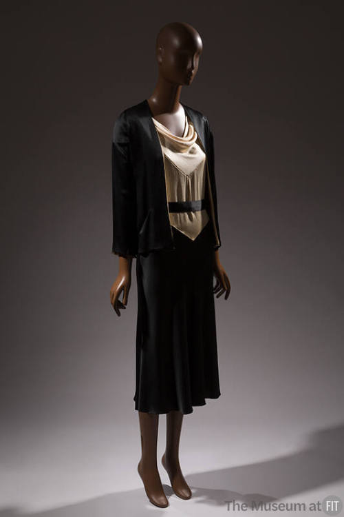 Black jacket over dress with white cowl neck bodice and black skirt 