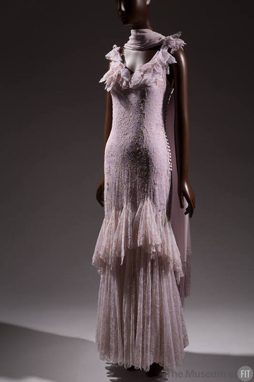 Light purple sleeveless floor length gown with floral pattern, v-neck ruffle flounce, and handk…