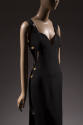 Black sleeveless evening dress with sweetheart neckline and oversize gold safety pins attached …