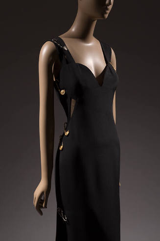 Black sleeveless evening dress with sweetheart neckline and oversize gold safety pins attached …