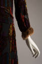 Hip and fur trimmed sleeve detail of black dress with multicolor geometric velvet pattern