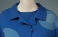Rollover collar and button of a blue coat with randomly placed medium blue and light blue inset…