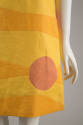 close up detail of red circle over yellow and orange horizonal panels at bottom of dress