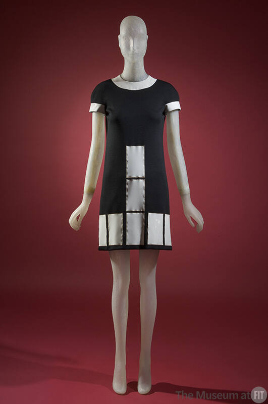 Black mini dress with white vinyl collar, short sleeves and white rectangles at front and hem