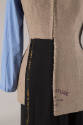 Detail view of beige linen tunic/jacket showing left panel tucked into black skirt