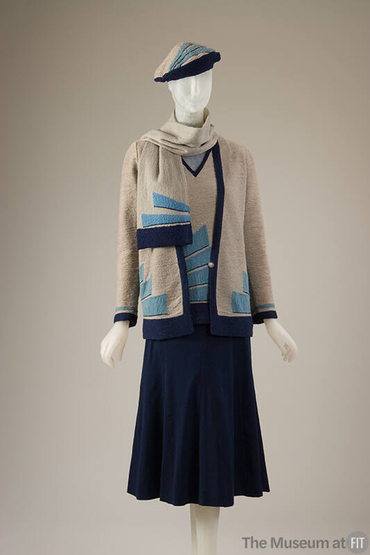 Knit ensemble of grey cardigan sweater with turquoise and navy blue wedge motifs, matching V-ne…