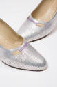 Detail view of silver evening pumps showing contrasting topstitching and eyelets with purple ta…