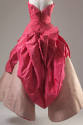 Back view of pink ballgown showing large sculpted panel of bodice extending to floor in V shape…