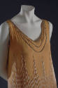 Detail view of orange evening dress showing rhinestones around armhole, neckline and white bead…