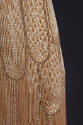 Detail view of orange evening dress showing fountain motif on skirt made of overlapping curved …