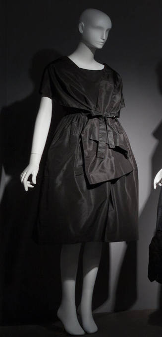 Black cocktail dress with fitted bodice, back wrap styling, dome skirt, and bow at waist
