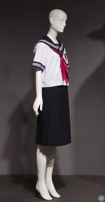 White short sleeve sailor top with blue trim and red scarf and navy blue pleated skirt