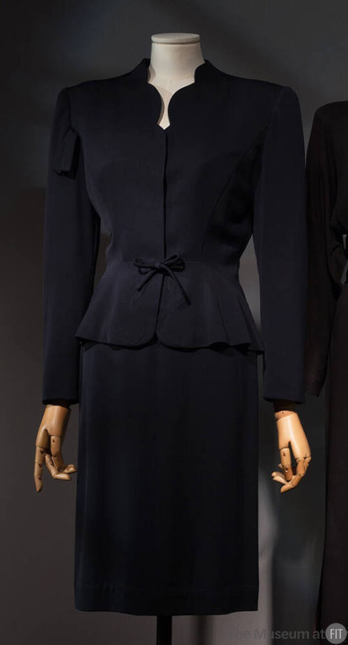 Navy blue suit:  jacket with scallop cut V-neck, shoulder pads, and below knee length straight …