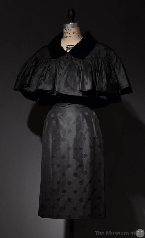 Dotted black cocktail dress and matching capelet with black velvet collar, button closure and s…