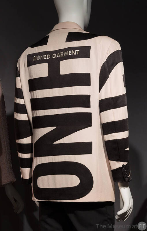 Back of taupe jacket with contrast black appliqué of oversize letters MOSCHINO placed throughou…
