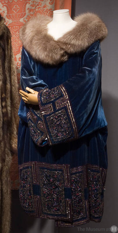 Deep teal blue knee length opera coat with gold metallic geometric border design, fur shawl col…