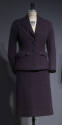 Purple suit with collared jacket with two patch pockets at hips and two large black buttons wit…