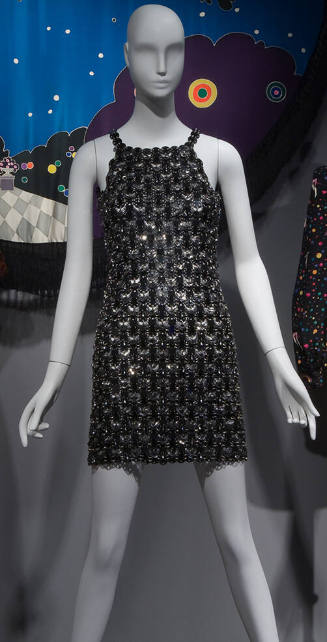 Sleeveless mini dress with halter neckline made of circular black discs attached by silver link…