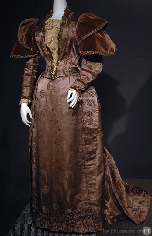 Mauve brocade floor length dress; cream bodice panel; voluminous velvet cap shoulder long sleev…