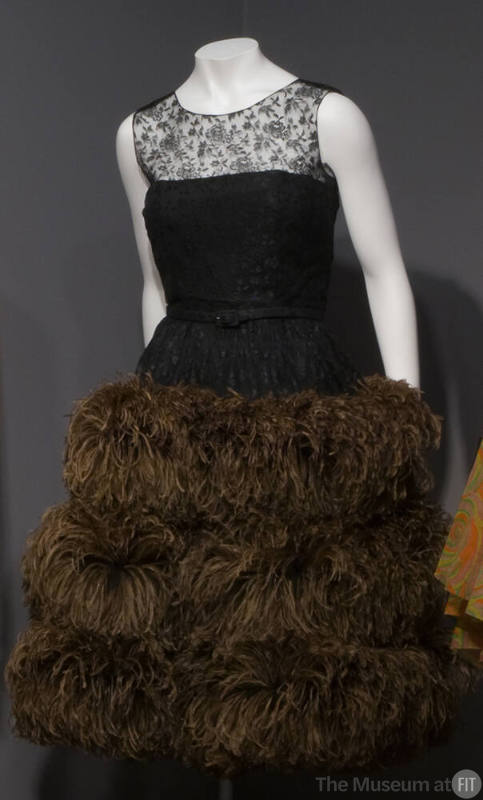 Sleeveless black lace evening dress with triple tier of long brown ostrich feathers on full ski…
