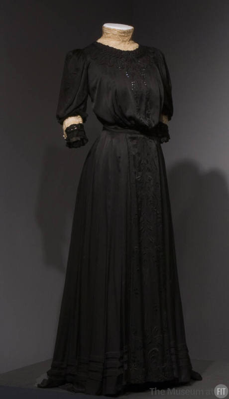 black two-piece dress: embroidered blouson bodice with leaf motifs, 3/4 length sleeves, and mat…