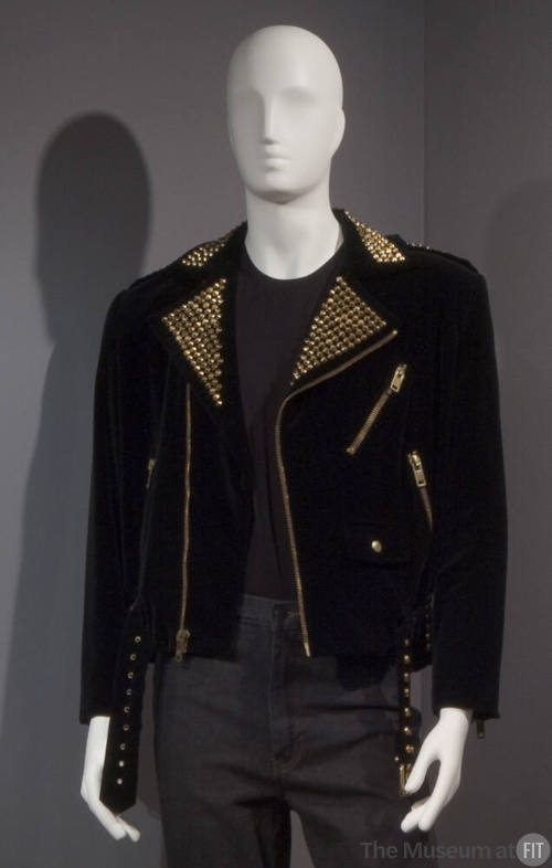 Black motorcycle style jacket with gold nail heads on notched lapels, gold zippers and studs on…
