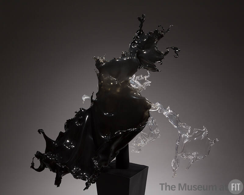 Black and grey acrylic dress in the from of liquid splashing on a black pedestal 