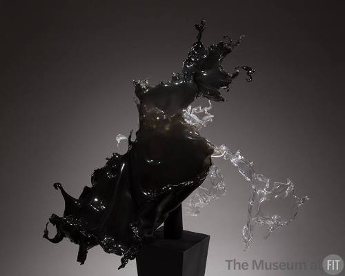 Black and grey acrylic dress in the from of liquid splashing on a black pedestal 