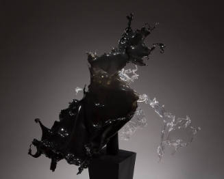 Black and grey acrylic dress in the from of liquid splashing on a black pedestal 