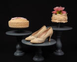 Two cake style hats and cream colored pumps on cake risers