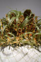 Detail view of corn hat showing embroidered ears of corn in yellow, orange and brown and green …