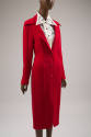 ¾ view of knee length red fitted coat dress with jacket styling, long stylized collar points an…