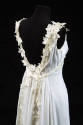 Detail view of white sleeveless evening dress showing center back bow and white leaf and berry …