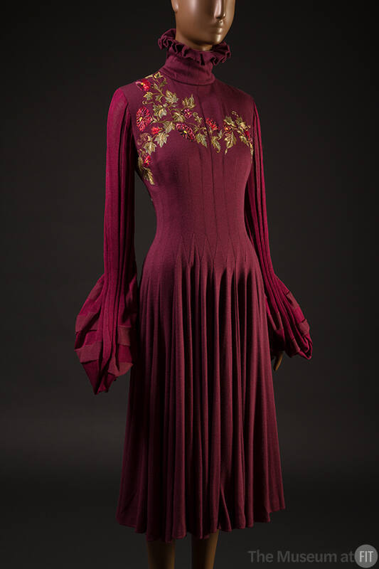 Red knit dress with long gathered sleeves, high turtleneck, embroidered flowers at chest, gathe…