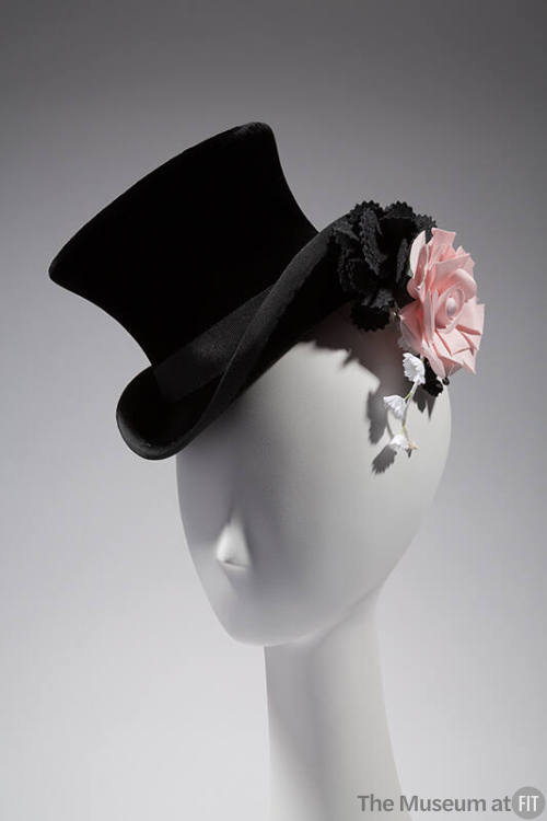 Black velvet top hat with black ribbon trim and hat band, pink rose at side